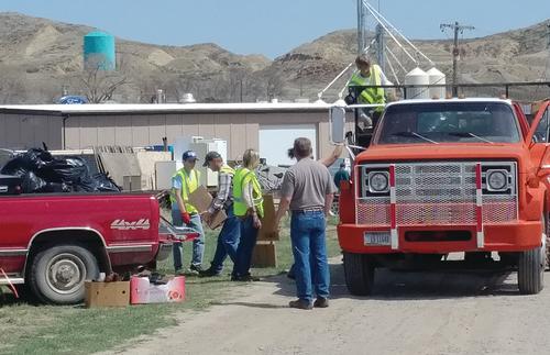 People are moving boxes and trash bags of recycled goods from one truck to another.